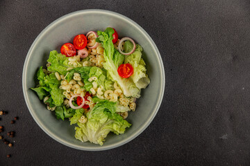 Pasta salad green leaf lettuce, tomato, pasta, onion fresh delicious gourmet food background on the table rustic food top view copy space keto and paleo diet vegan and vegetarian food