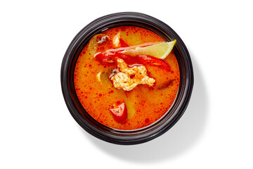 Tom yam soup with chicken and lime in black bowl on white background