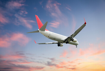 Airplane flying in beautiful sky with clouds at sunset
