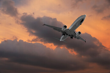 Airplane flying in beautiful sky with clouds at sunset