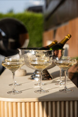 A Beautiful Arrangement of Elegant Champagne Glasses on a Marble Table with an Ice Bucket and Champagne Bottles Reflecting Warm Sunlight