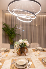 Elegant Dining Setup with Stylish Lighting and Floral Centerpiece in a Modern Decorated Space Featuring Tasteful Tableware and Atmosphere
