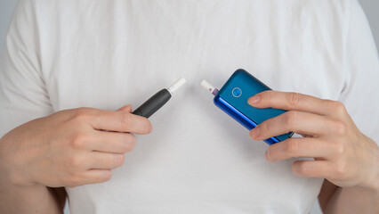 A woman compares two different tobacco heating systems. Electronic cigarette.