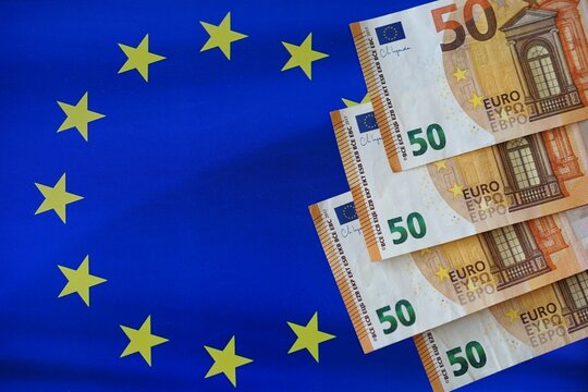 Stack of 50 euro banknotes on EU flag symbolizing European economy and finance. Euro money background. Concept of Finance and Business, economic unity, currency exchange, interest rates