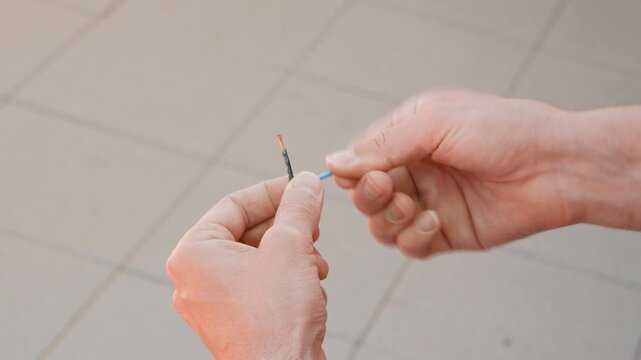 Man is twisting three non insulated copper wire