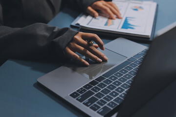 Close up of business woman hands typing on laptop computer and digital tablet, searching and surfing the internet on office desk, online working, telecommuting, freelancer at work concept
