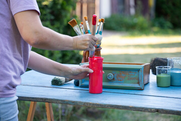 Woman painting a wooden furniture outdoors, an eco-friendly re-use business.