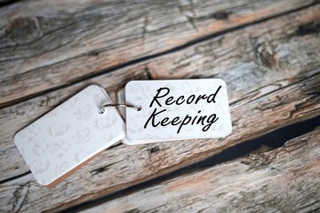 Record Keeping, text on a small notebook isolated on a wooden table.
