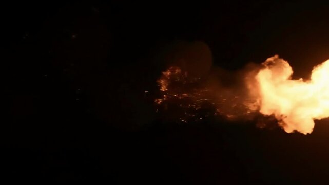 Powerful fiery blast erupting against a pitch black night sky bright orange yellow flame jet of intense burning heat energy and inferno hot fire shooting right 
