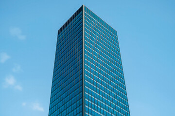 Fototapeta premium Tall Glass Skyscraper With Blue Windows Reflecting Sky In Minimal Urban Composition
