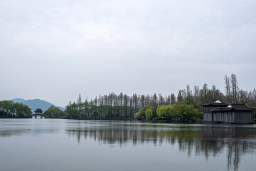 Obraz premium West Lake, Hangzhou, China. Traditional Pavilion bridge, spring trees, cloudy sky and calm water.