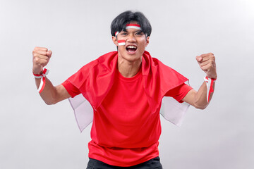 Naklejka premium Determined young man in red shirt and Indonesian flag cape, clenching fists and shouting with spirit, celebrating independence day with pride, passion, and full of national energy!