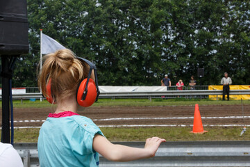 Excitement builds as a young girl watches a thrilling race event at a motorsport track on a warm...
