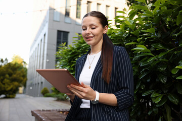 Successful businesswoman with tablet near office building