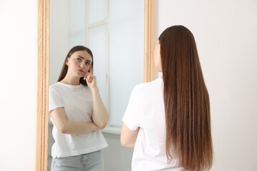 Fototapeta premium Beautiful young woman posing near mirror indoors