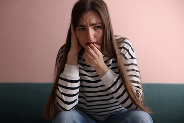 Worried woman suffering from paranoia on sofa indoors