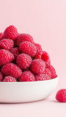 A delightful close-up of fresh, plump raspberries arranged on a textured pink plate. The image emphasizes the fruit's vibrant color and delicate texture, suggesting a healthy