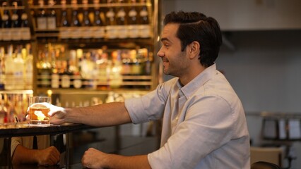 Smiling smart man drinking cocktail in Old fashioned with enjoy in cheers with friends or stranger...