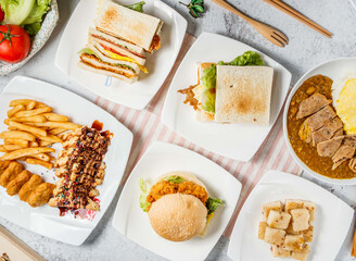 Breakfast and Lunch Spread Asian and Western Food Assortment with Waffle, Chicken Nuggets, fries, Curry Pork Chop Rice, Omelette, Toast Sandwich, Carrot Cake, Pork Toast and Chicken Fillet Burger