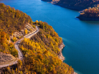 Scenic autumn road winding through vibrant fall foliage and mountains near a lake