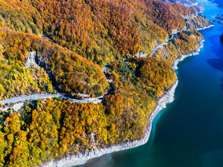 Scenic autumn road winding through vibrant fall foliage and mountains near a lake