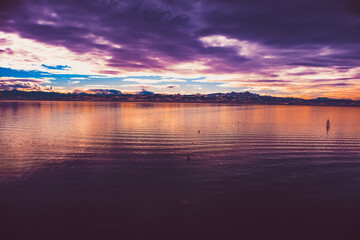 Fototapeta premium Calm lake at sunset with a purple-orange sky.