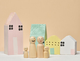 A row of wooden houses in front of them are four wooden figures symbolizing a family.