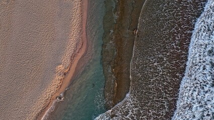 Overhead drone view of beach with clear turquoise waves in Crete, Greece