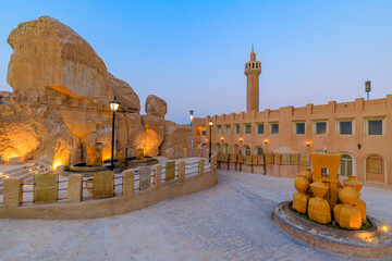 Illuminated rock caves and mosque of Jabal Al Qarah mountain with fountain at dusk in Al Ahsa oasis, Saudi Arabia, showing local culture and heritage