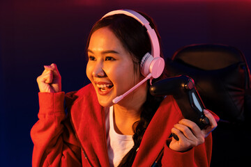 Host channel of smiling beautiful Asian girl streamer with joystick playing with raising fist up...