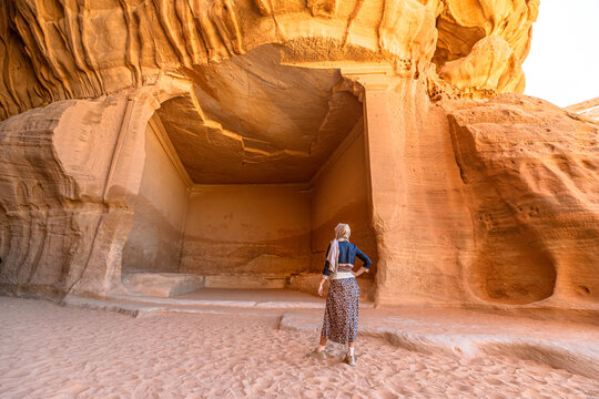 Woman admiring Jabal Ithlib rock-cut tombs in archaeological site of Hegra, the Diwan and Siq in Madinah Province. UNESCO Heritage site showcasing Nabataean architecture and history of Saudi Arabia