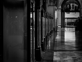 Black and white shot of a historic corridor with tall mirrors and columns inside a building.