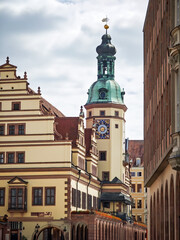 Historic town hall with towers and carillon in the center of an old town. Warm lighting and narrow alley view.
