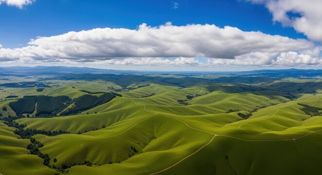 Expansive green rolling hills under a vast blue sky with dramatic white clouds
