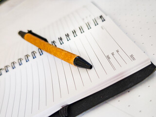 Notebook with a daily planner layout, a ballpoint pen placed in the middle of the page.