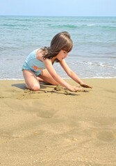 little girl is playing with sand on the beach. High quality photo