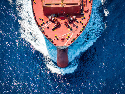 Aerial overhead view of a bow from a large container cargo or tanker ship sailing with speed over the ocean