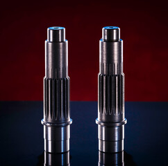 Two polished metal shafts stand on a dark surface