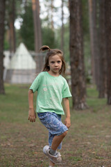 Fototapeta premium a girl child walking in a pine forest, one leg bent, looking into the distance