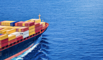 Aerial view of the bow of industrial container cargo ship sailing over the ocean with copy space as...