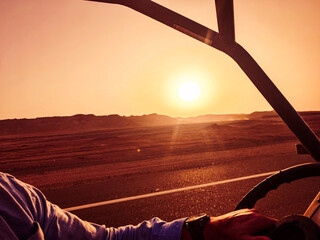 From the buggy, the view falls on the setting sun over the sandy desert – adventure meets...