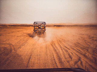  A lone buggy drives through endless desert terrain – dust and freedom..
