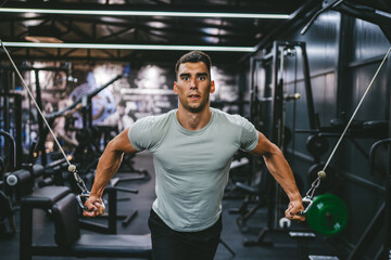 fit man chest stretching workout on cable machine in the gym