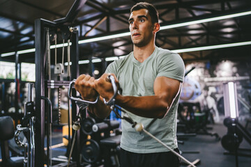 athlete man do exercise for triceps on the exercise cable machine