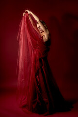 Naklejka premium Elegant dancer gracefully poses with flowing fabric in a vibrant red environment during a performance