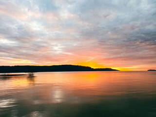 A sunset over calm water reflecting sky and light – peaceful atmosphere.