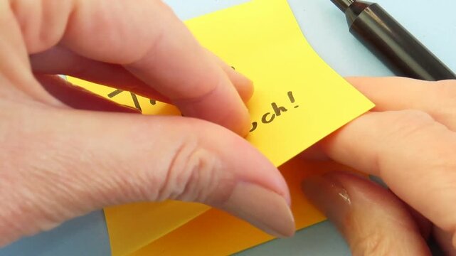 Woman hands holding a yellow sticky note with the message "Thank you so much!" and a smile.