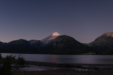 long-exposure of snow-capped Lanín Volcano mirrored in Lake Huechulaufquen at dusk in Patagonia.
