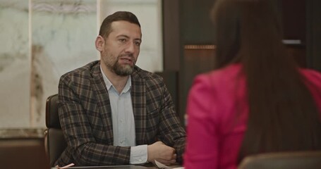 Two senior business people negotiating a contract in a modern boardroom, discussing terms and conditions. - Powered by Adobe