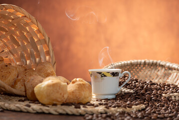 Cheese bread and coffee, delicious Brazilian cheese bread and a beautiful cup of coffee on a rustic table and coffee beans, abstract background, selective focus.